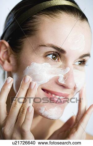 Stock Image - Woman putting face mask on. Fotosearch