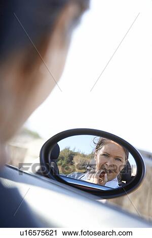 Stock Image - Woman putting on lipstick in car. Fotosearch