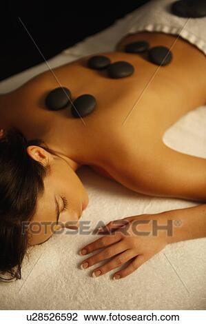 Stock Image - Woman receiving hot stone massage. Fotosearch
