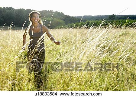 Picture - Woman running in a field. Fotosearch