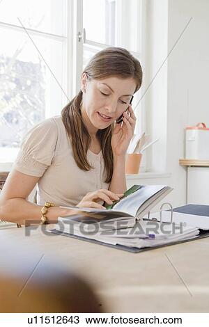 Woman sitting at table using phone View Large Photo Image Stock Image - Woman sitting at table using phone. Fotosearch