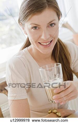 Woman sitting at table with a beverage View Large Photo Image Stock Photo - Woman sitting at table with a beverage. Fotosearch