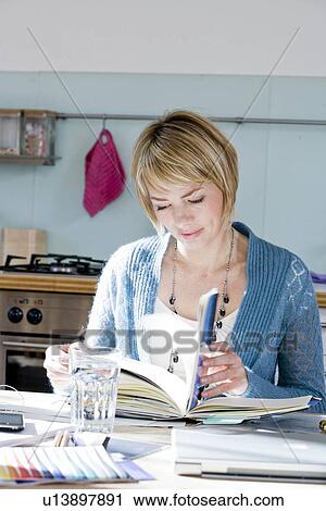 Woman sitting in kitchen reading View Large Photo Image Stock Image - Woman sitting in kitchen reading. Fotosearch