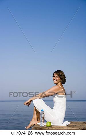 Woman sitting on a pier View Large Photo Image Stock Photograph - Woman sitting on a pier. Fotosearch