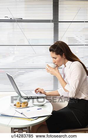 Stock Photography - Woman sitting with laptop at cafe table. Fotosearch