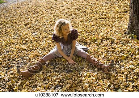 Stock Photo - Woman sitting within heaps of leaves. Fotosearch