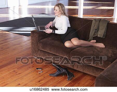 Stock Photography - Woman using laptop on sofa. Fotosearch