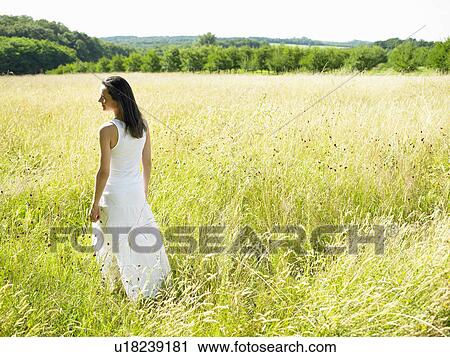 Stock Image - Woman walking in a field. Fotosearch