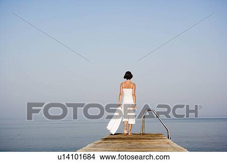 Picture - Woman walking on a pier. Fotosearch