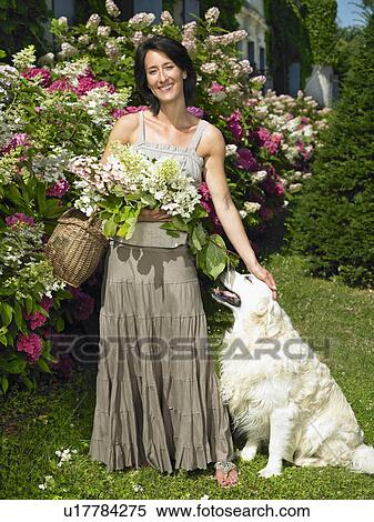 Stock Photography - "Woman with her dog, holding flowers". Fotosearch