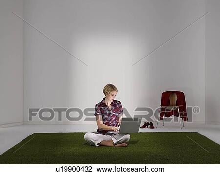 Stock Image - Woman working on laptop in green office. Fotosearch