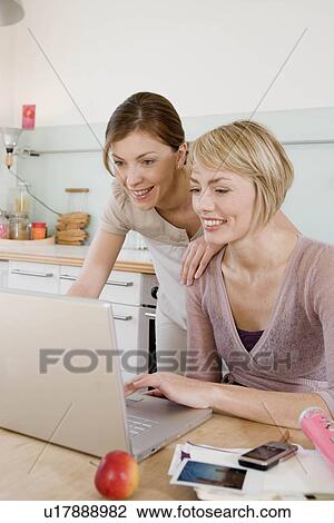 Women in kitchen using laptop View Large Photo Image Stock Image - Women in kitchen using laptop. Fotosearch