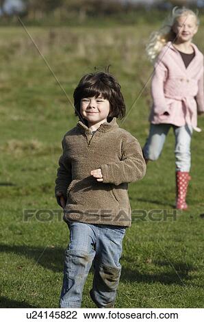 Stock Image - Young boy and girl running in field. Fotosearch