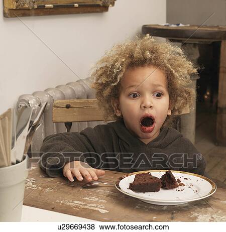 Stock Photo - Young boy eating chocolate cake. Fotosearch
