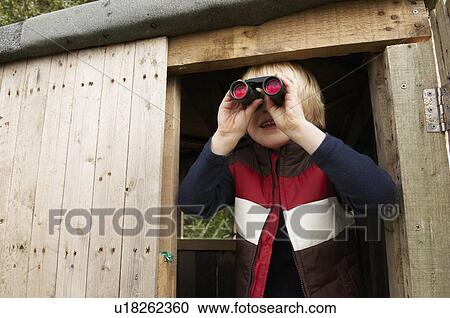 Stock Image - Young boy in treehouse with binoculars. Fotosearch