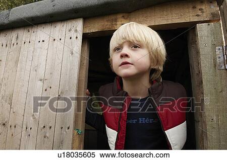 Stock Photography - Young boy looking out treehouse door. Fotosearch