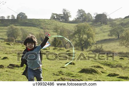 Young boy running with kite in field View Large Photo Image Stock Photograph - Young boy running with kite in field. Fotosearch