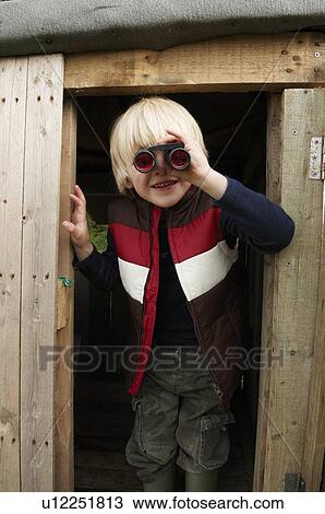 Stock Image - Young boy with binoculars in treehouse. Fotosearch