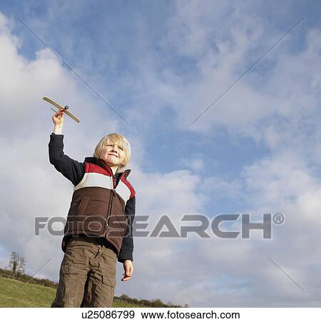 Stock Photo - Young boy with toy plane in countryside. Fotosearch