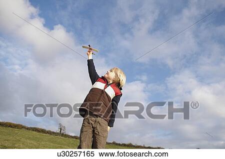 Stock Photography - Young boy with toy plane in countryside. Fotosearch