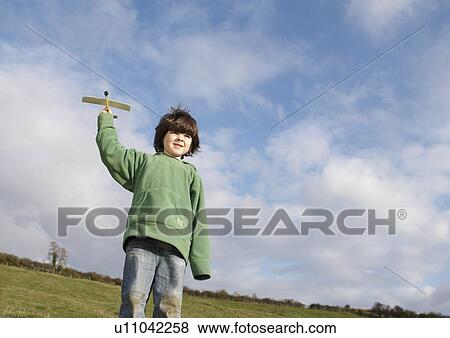 Stock Photo - Young Boy with toy plane in field. Fotosearch