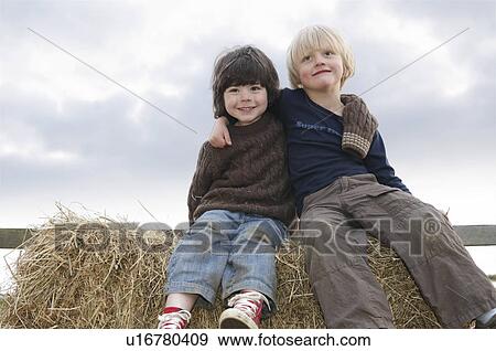 Stock Photo - Young boys sitting on hay bales. Fotosearch