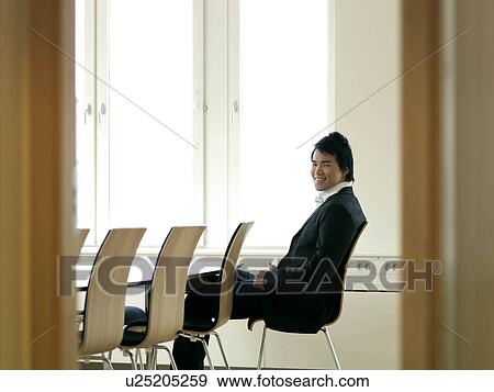 Stock Photo - Young business man by table. Fotosearch