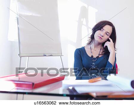 Young businesswoman sitting at desk View Large Photo Image Stock Image - Young businesswoman sitting at desk. Fotosearch