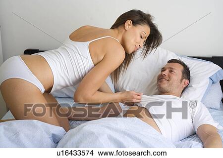 Picture - Young couple at home relaxing in bed. Fotosearch