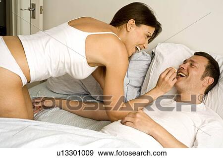 Young couple at home relaxing in bed View Large Photo Image Stock Photo - Young couple at home relaxing in bed. Fotosearch