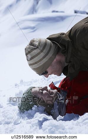 Stock Photo - Young couple lying in snow. Fotosearch