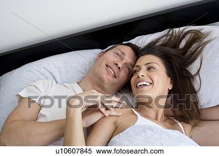 Young couple relaxing in bed View Large Photo Image Stock Photography - Young couple relaxing in bed. Fotosearch