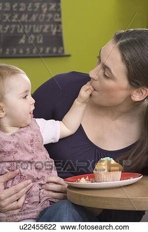 Stock Image - Young girl feeding her mother with cake. Fotosearch