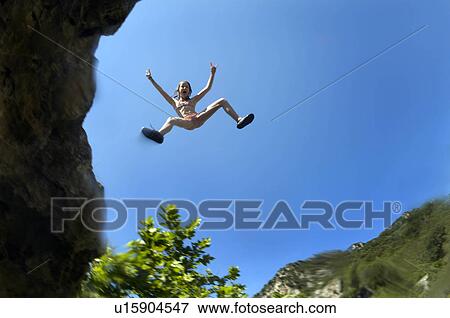 Young girl jumping of a cliff View Large Photo Image Stock Photo - Young girl jumping of a cliff. Fotosearch