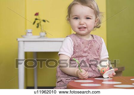 Stock Image - Young girl on table with sundae. Fotosearch