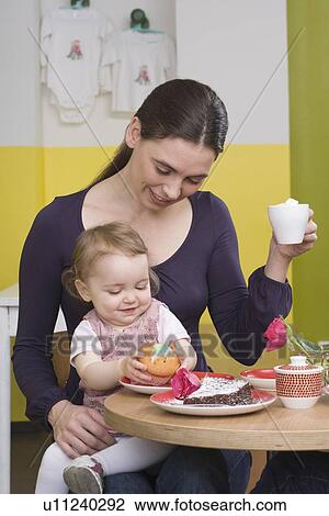 Stock Image - "Young girl with cake, on mothers lap". Fotosearch