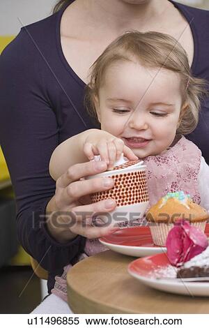 Stock Photography - Young girl with sugarcane on mothers lap. Fotosearch