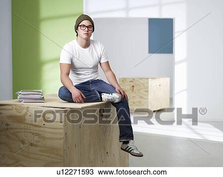 Stock Image - Young man sitting on box. Fotosearch