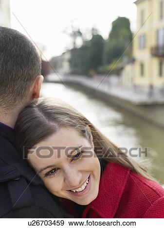 Stock Photo - Young woman embracing partner. Fotosearch