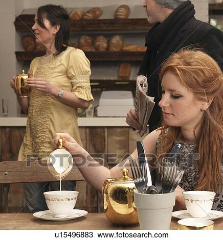 Stock Image - Young woman having tea in café. Fotosearch
