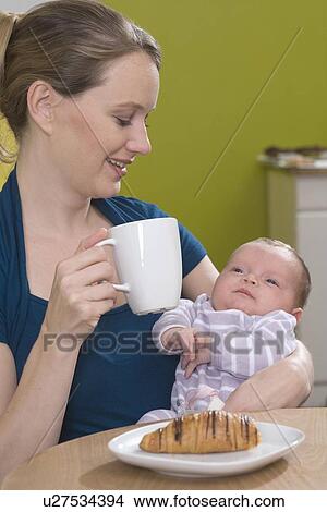 Picture - Young woman in coffee shop with baby. Fotosearch