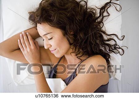 Stock Photograph - Young woman sleeping in bed. Fotosearch