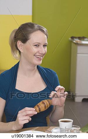 "Young woman with croissant, laughing" View Large Photo Image Picture - "Young woman with croissant, laughing". Fotosearch