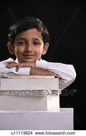 Picture - A boy leaning on stack of books. Fotosearch