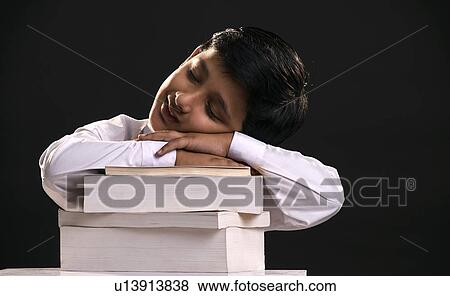Stock Photo - A boy sleeps on a stack of books. Fotosearch