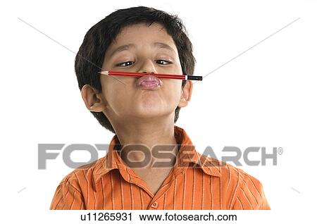 Stock Image - A boy with a pencil between his nose and lips. Fotosearch