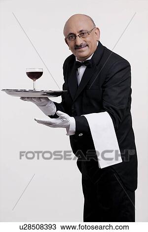 Stock Image - A butler serving a drink. Fotosearch