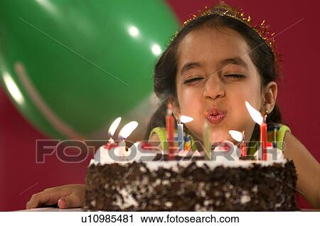 Stock Image - A girl blowing the candles. Fotosearch