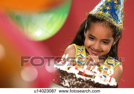 Stock Photo - A girl in a party cap and birthday cake. Fotosearch