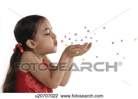 Stock Image - A little girl blowing confetti. Fotosearch